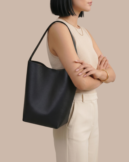 Woman carrying the Léa Bucket Bag in black pebbled cowhide, side profile, half body