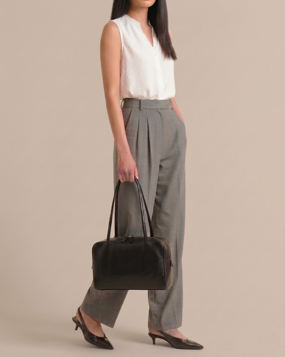 Woman carrying the Adèle Bowling Bag in black, side profile, full body