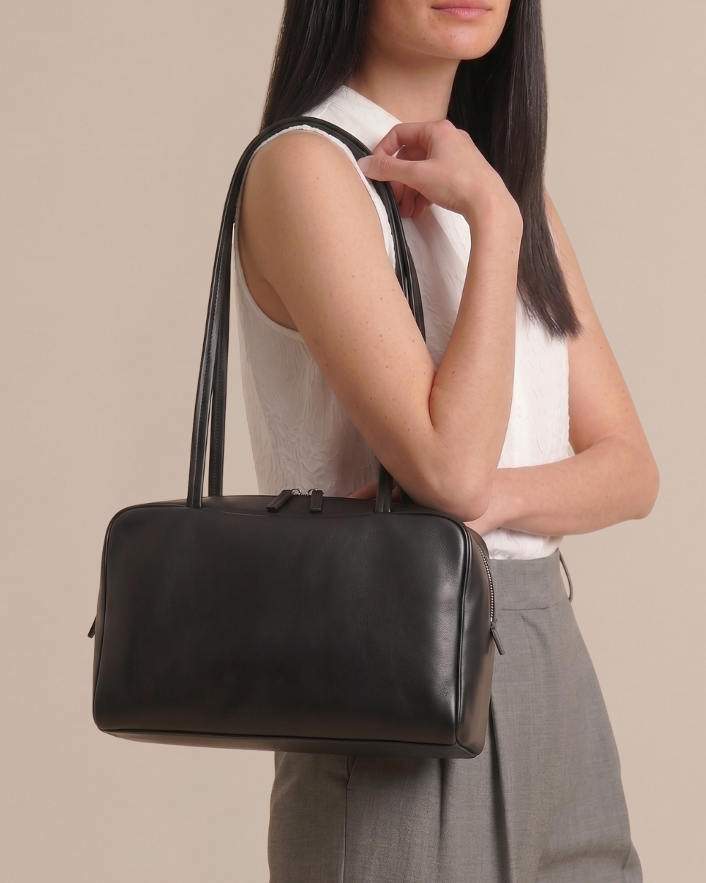Woman carrying the Adèle Bowling Bag in black, side profile, half body